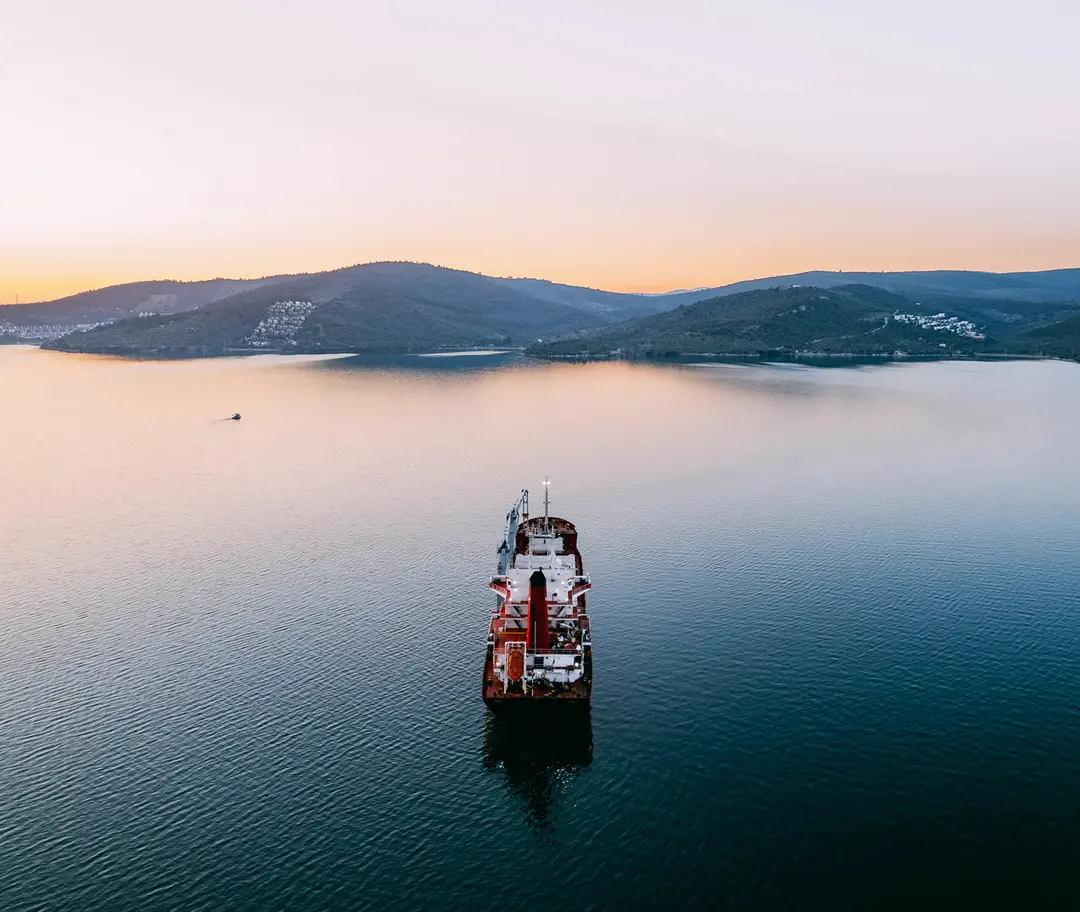 Ship sailing at dusk with mountains
