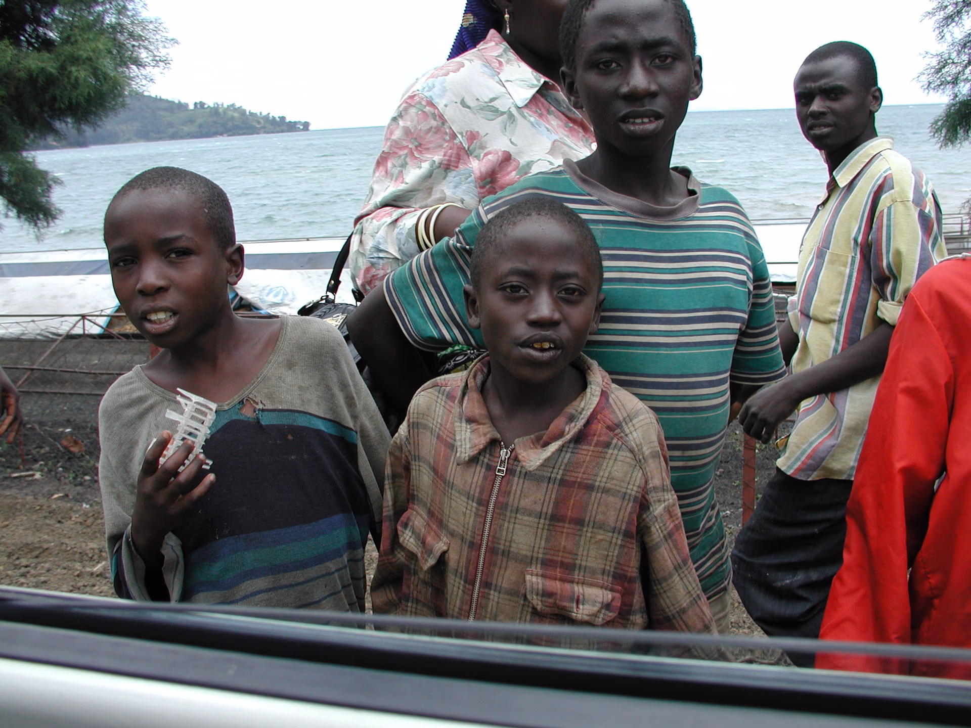 Four children standing near a shoreline with the ocean in the background.