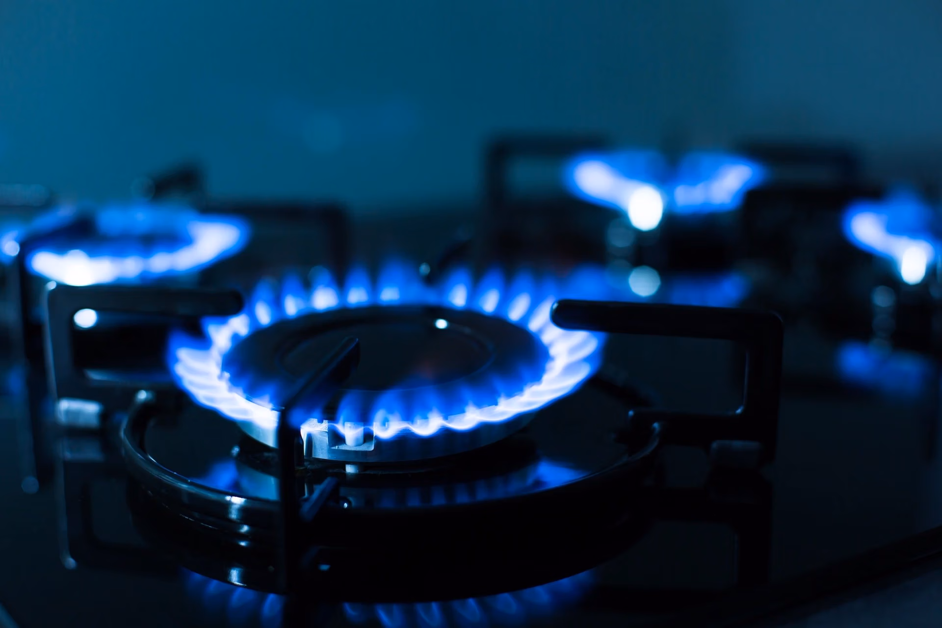Blue flames burning on a black gas stovetop.
