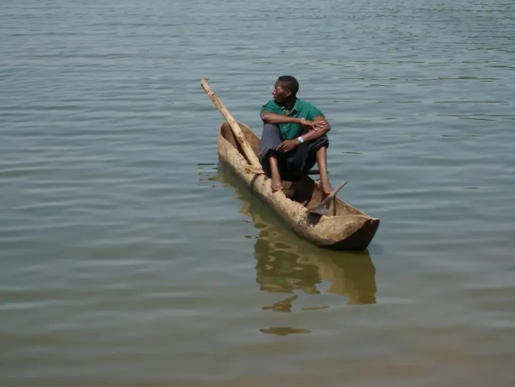 Man in wooden dugout canoe on water