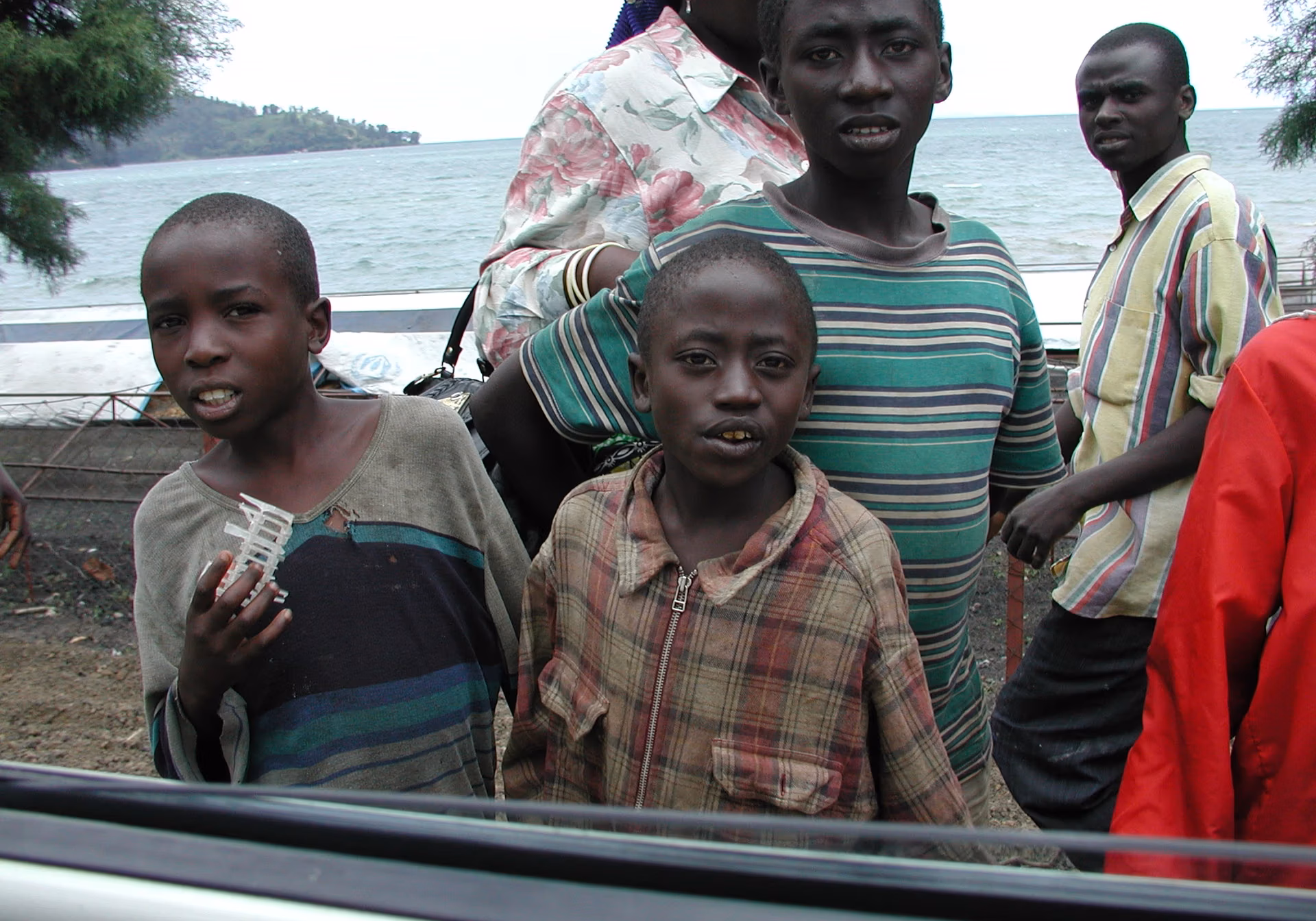 Four children standing near a shoreline with the ocean in the background.