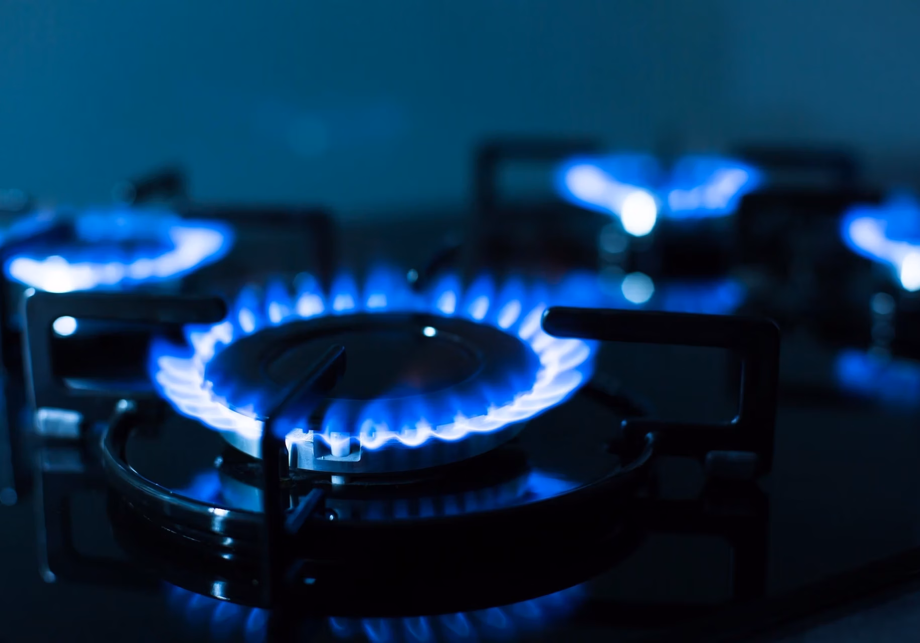 Blue flames burning on a black gas stovetop.
